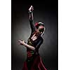 young woman dancing flamenco with castanets on black