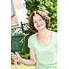Senior woman smiling holding rake and gardening outside