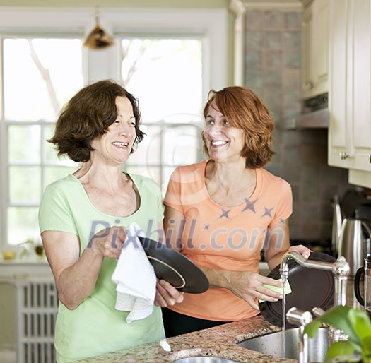 Mother and daughter doing dishes in kitchen at home Mother and daughter doing dishes in kitchen at home