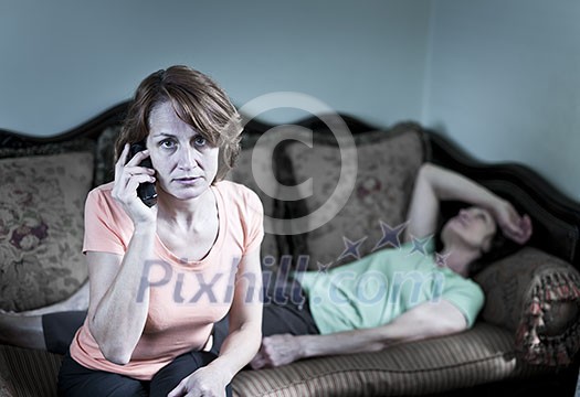 Concerned woman with sick senior mother calling emergency