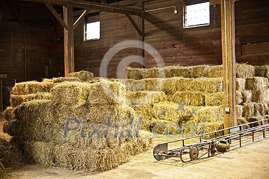 Interior of barn with hay bales stacks and conveyor belt