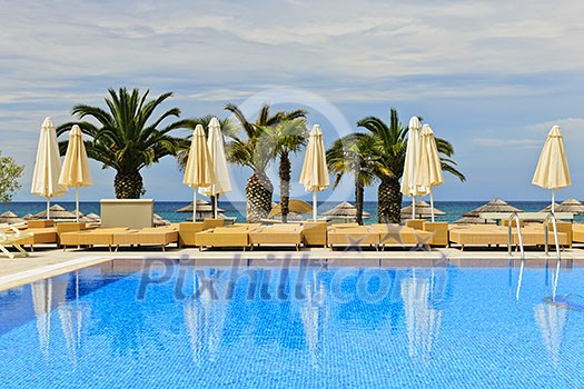 Idyllic swimming pool at tropical resort with palm trees in Greece