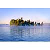 Island with pine trees in morning fog on lake at sunrise