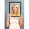 Portrait of smiling young woman holding picture frame on grey background
