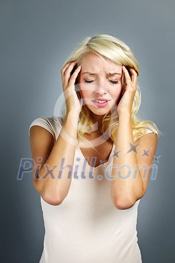 Upset young blonde woman with headache on grey background