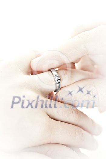 Closeup of hands placing engagement ring on finger Closeup of hands placing engagement ring on finger