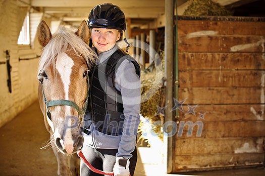 Portrait of teenage girl with horse in stable