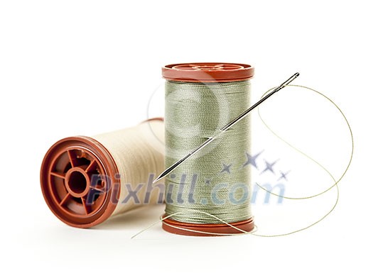 Two spools of thread with needle for sewing isolated on white background