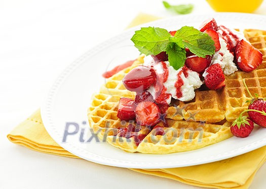 Plate of belgian waffles with fresh strawberries and whipped cream