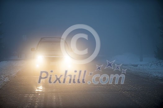 Bright headlights of a car driving on foggy winter road Bright headlights of a car driving on foggy winter road