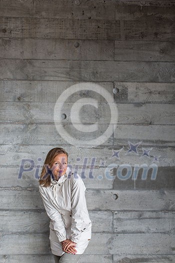 Pretty, young woman in front of a concrete wall (copy space available; color toned image)