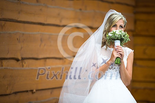 Portrait of a gorgeous young bride on her wedding day - smelling the flowers in her bouquet, enjoying the big day, feeling happy