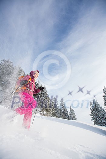 Young woman snowshoeing in high mountains, enjoying a lovely day