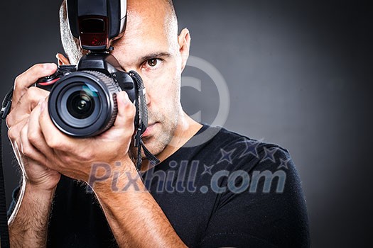 Young, pro male photographer in his studio during a photo shoot (color toned image; shallow DOF)