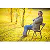 Portrait of a senior man outdoors, sitting on a bench in a park (shallow DOF; color toned image)