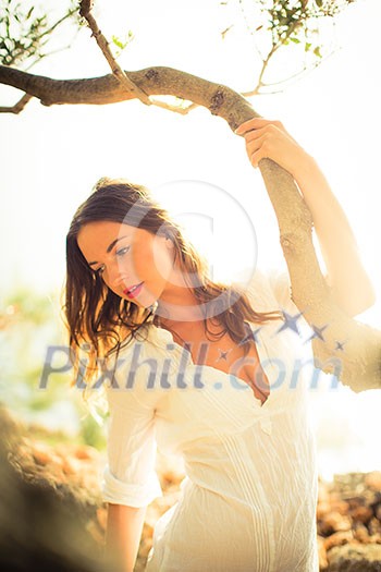 Attractive, young brunette on the beach, amid olive trees, looking both sensual and natural