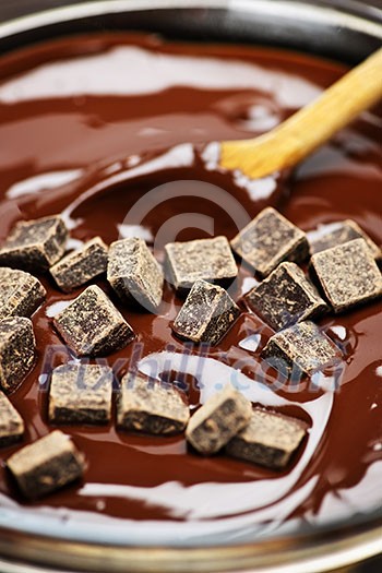 Wooden spoon stirring melting rich chocolate chunks Wooden spoon stirring melting rich chocolate chunks