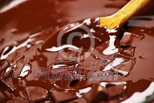 Wooden spoon stirring melting rich chocolate chunks Wooden spoon stirring melting rich chocolate chunks