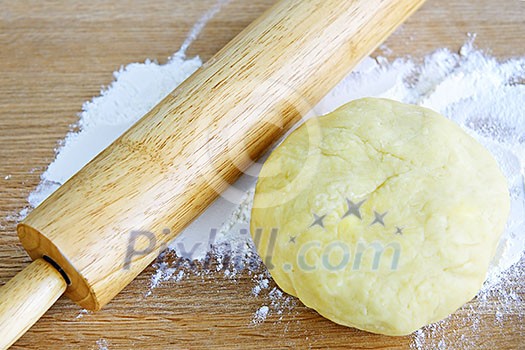 Wooden rolling pin and ball of cookie dough with flour Wooden rolling pin and ball of cookie dough with flour