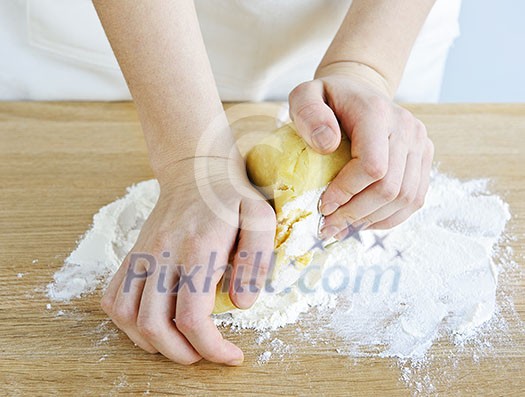 Hands kneading ball of dough with flour on cutting board Hands kneading ball of dough with flour on cutting board