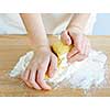 Hands kneading ball of dough with flour on cutting board