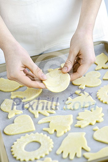 Chef placing cutout cookie dough shapes on tray for baking Chef placing cutout cookie dough shapes on tray for baking