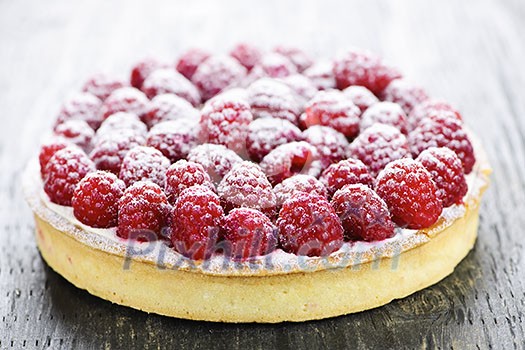 Fresh dessert fruit tart covered in raspberries