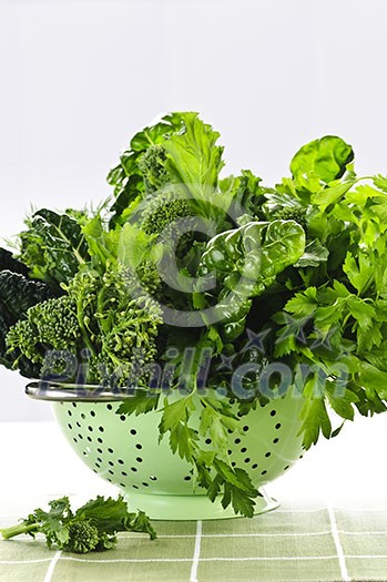 Dark green leafy fresh vegetables in metal colander