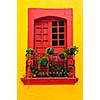 Red painted window with plants and wrought iron railing in Mexico