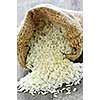 Raw long grain white rice grains in burlap bag