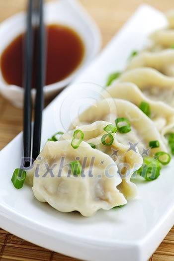 Plate of steamed dumplings with soy sauce and chopsticks Plate of steamed dumplings with soy sauce and chopsticks