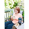 Happy woman relaxing with coffee and cookies on deck chair in backyard at home