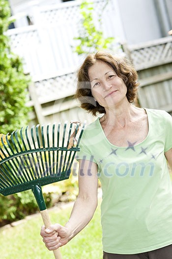 Senior woman smiling holding rake for yard work outside Senior woman smiling holding rake for yard work outside