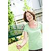 Senior woman smiling holding rake for yard work outside