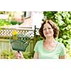 Senior woman smiling holding rake for yard work outside