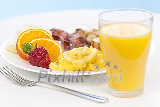 Healthy breakfast of scrambled eggs bacon fruit and orange juice