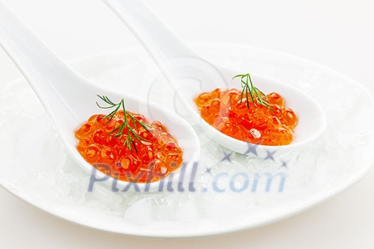 Closeup of caviar with dill garnish in two white spoons on ice