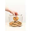 Hand taking chocolate chip cookie from glass jar