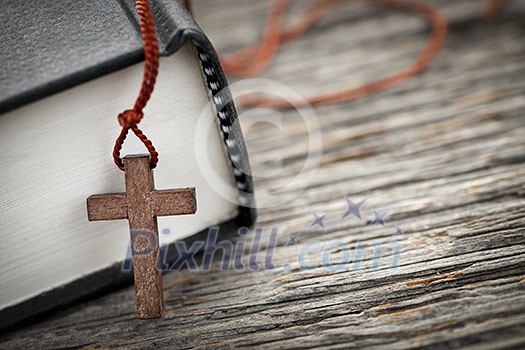 Closeup of wooden Christian cross necklace next to holy Bible Closeup of wooden Christian cross necklace next to holy Bible