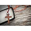 Closeup of wooden Christian cross necklace next to holy Bible