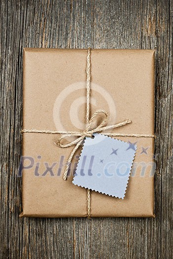 Gift package and card in brown paper wrapper tied with string on rustic wood background Gift package and card in brown paper wrapper tied with string on rustic wood background