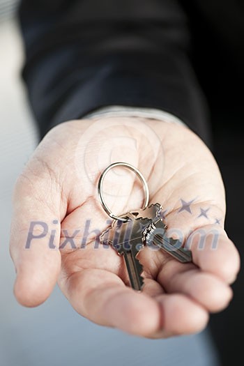Male hand offering two new house keys on key ring Male hand offering two new house keys on key ring
