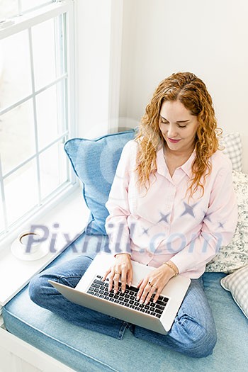 Caucasian woman using laptop computer sitting on couch at home Caucasian woman using laptop computer sitting on couch at home
