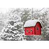 Red bird house hanging outdoors in winter covered with snow
