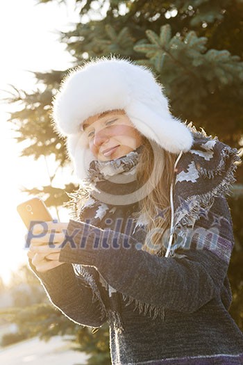 Portrait of teenage girl holding mobile phone outside in winter