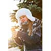 Portrait of teenage girl holding mobile phone outside in winter