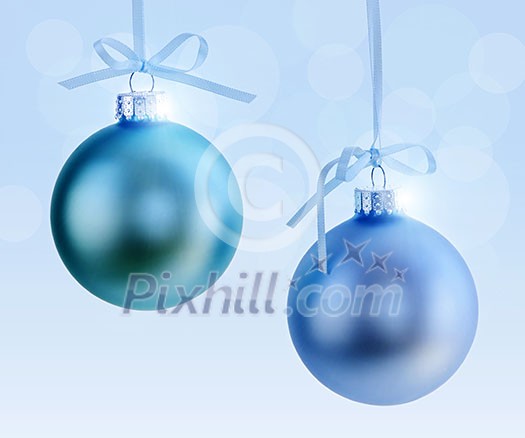 Two Christmas decorations hanging on ribbons with blue background