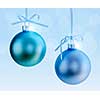 Two Christmas decorations hanging on ribbons with blue background