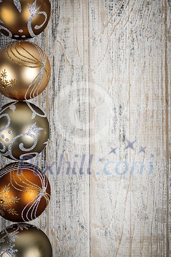 Row of golden Christmas balls with festive designs on wooden background