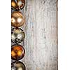 Row of golden Christmas balls with festive designs on wooden background